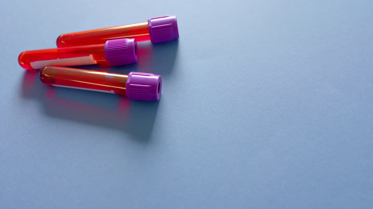 Close up of blood samples on blue background with copy space, slow motion