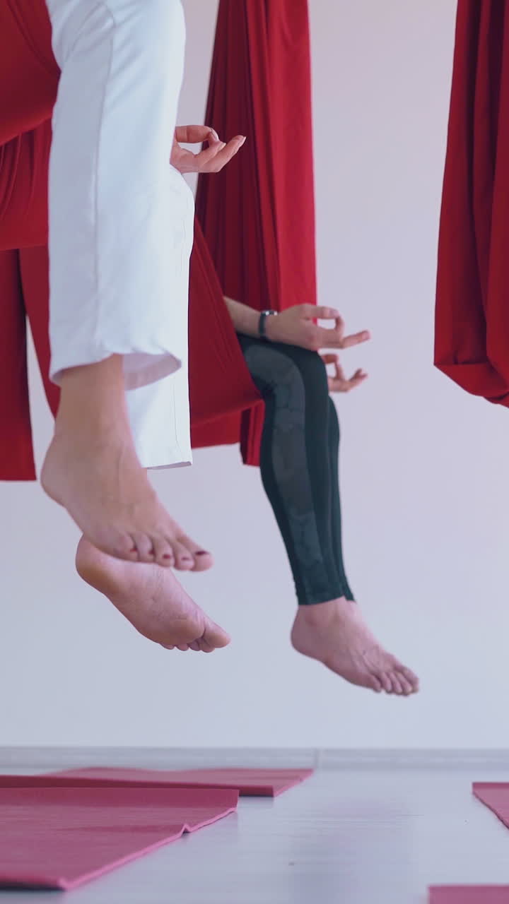 motion along women group with slim legs in leggings and bare feet practicing butterfly fly yoga pose close view