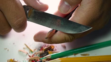 Footage-of-hands-slowly-sharpening-a-pencil-and-some-coloured-pencils-with-a-sharp-knife