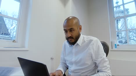 Asian-Indian-Male-typing-on-laptop-at-desk-in-office