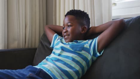 african american boy smiling while sitting on the couch at home
