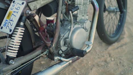 hombre con botas negras altas lucha para arrancar motocicleta retro retro chopper en el desierto