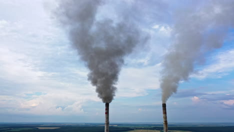 view from the drone at the old aged weathered tall industrial factory chimney with smoke over it. cloudy sky background