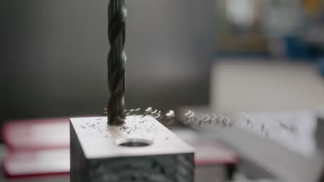 close up of a drill bit working on a block of aluminium metal block spinning access material