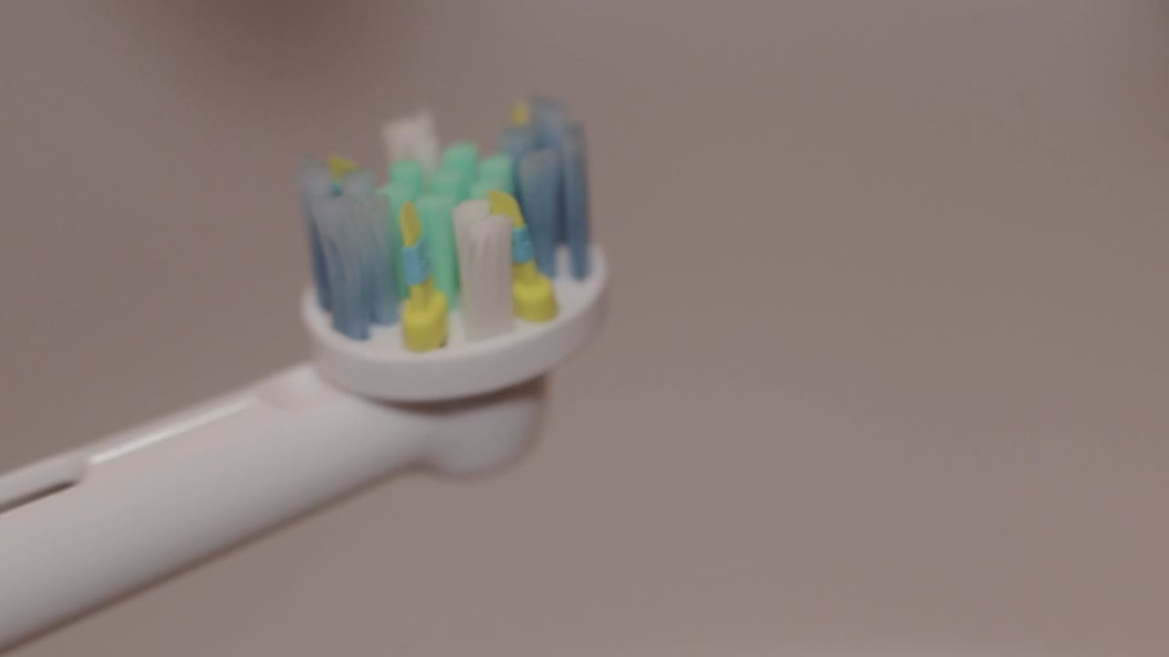 Detail shot of mint toothpaste layered on an electric toothbrush