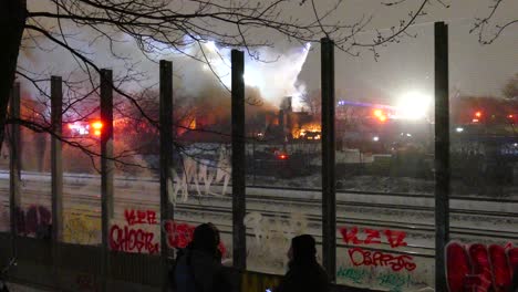 Gente-Mirando-Un-Gran-Incendio-Con-Muchos-Camiones-De-Bomberos-En-La-Escena