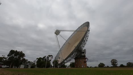 large satellite dish rotates under a cloudy sky