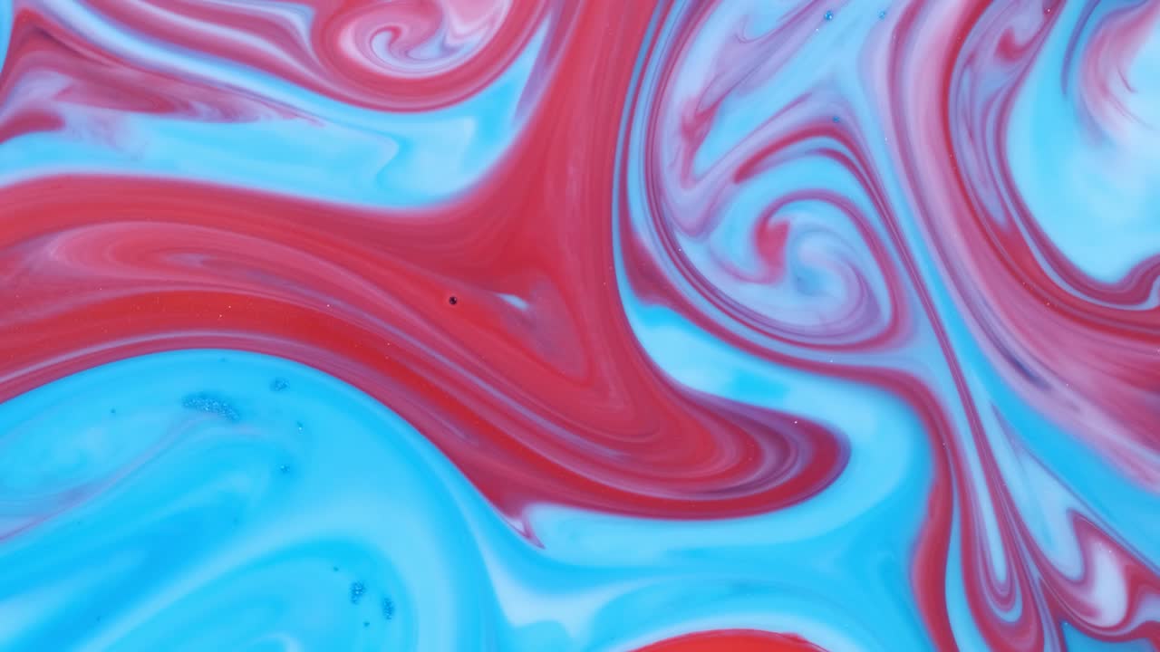 Mixing red acrylic paints in liquid.