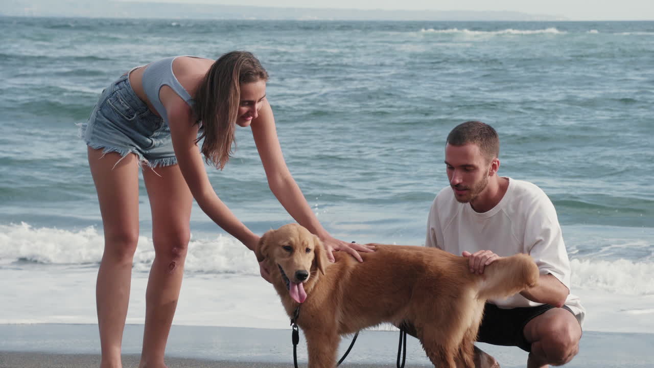 pareja caucásica y perro cerca del mar