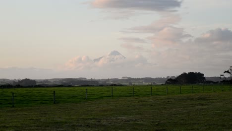 snow capped peak of mount taranaki visible after a rainstorm during a vibrant sunset