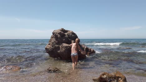 Young-Girl-Kid-Climb-Over-Isolated-Boulder-In-Playa-de-Cabo-de-Gata,-Spain