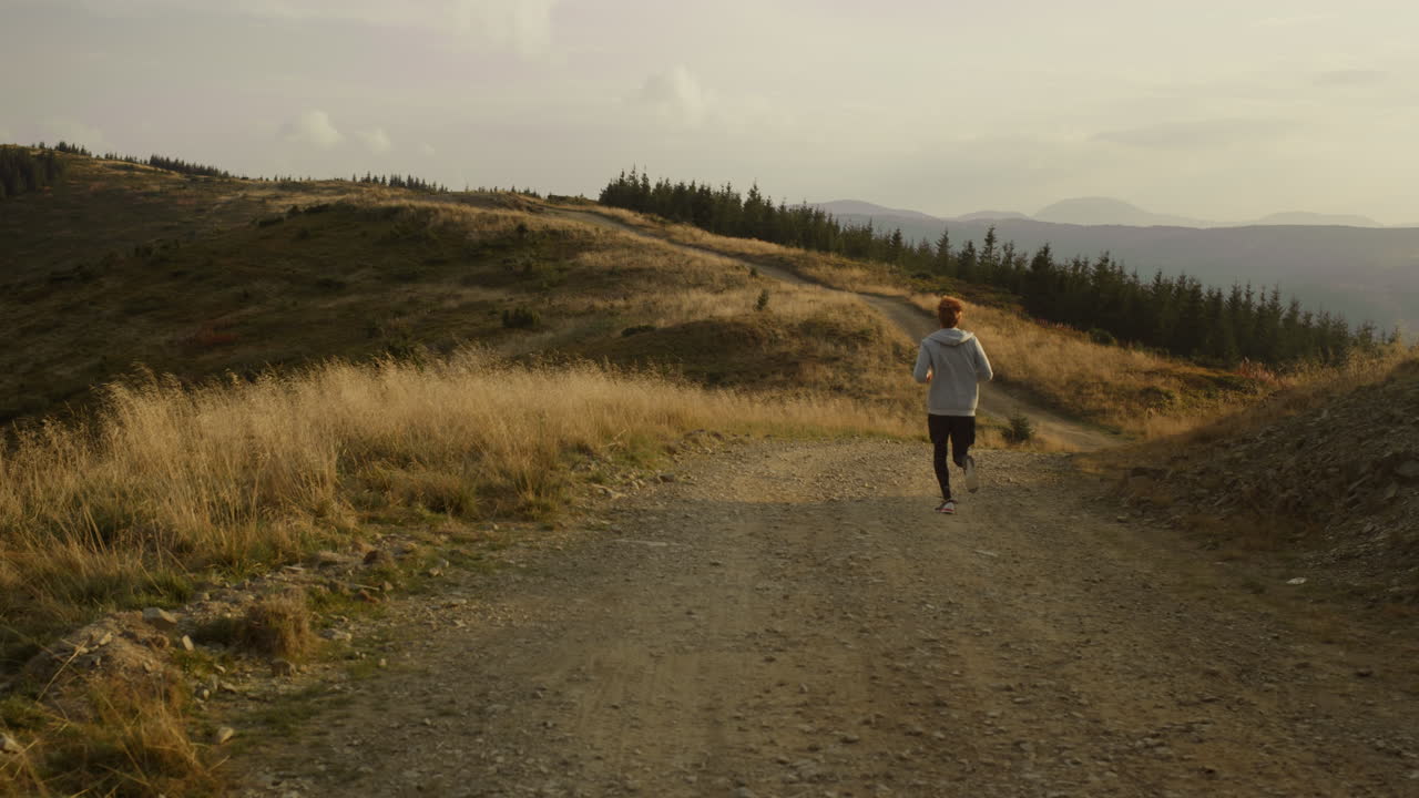 산에서 달리는 남자 운동선수. 스포티한 남자가 더러운 길에서 훈련합니다.