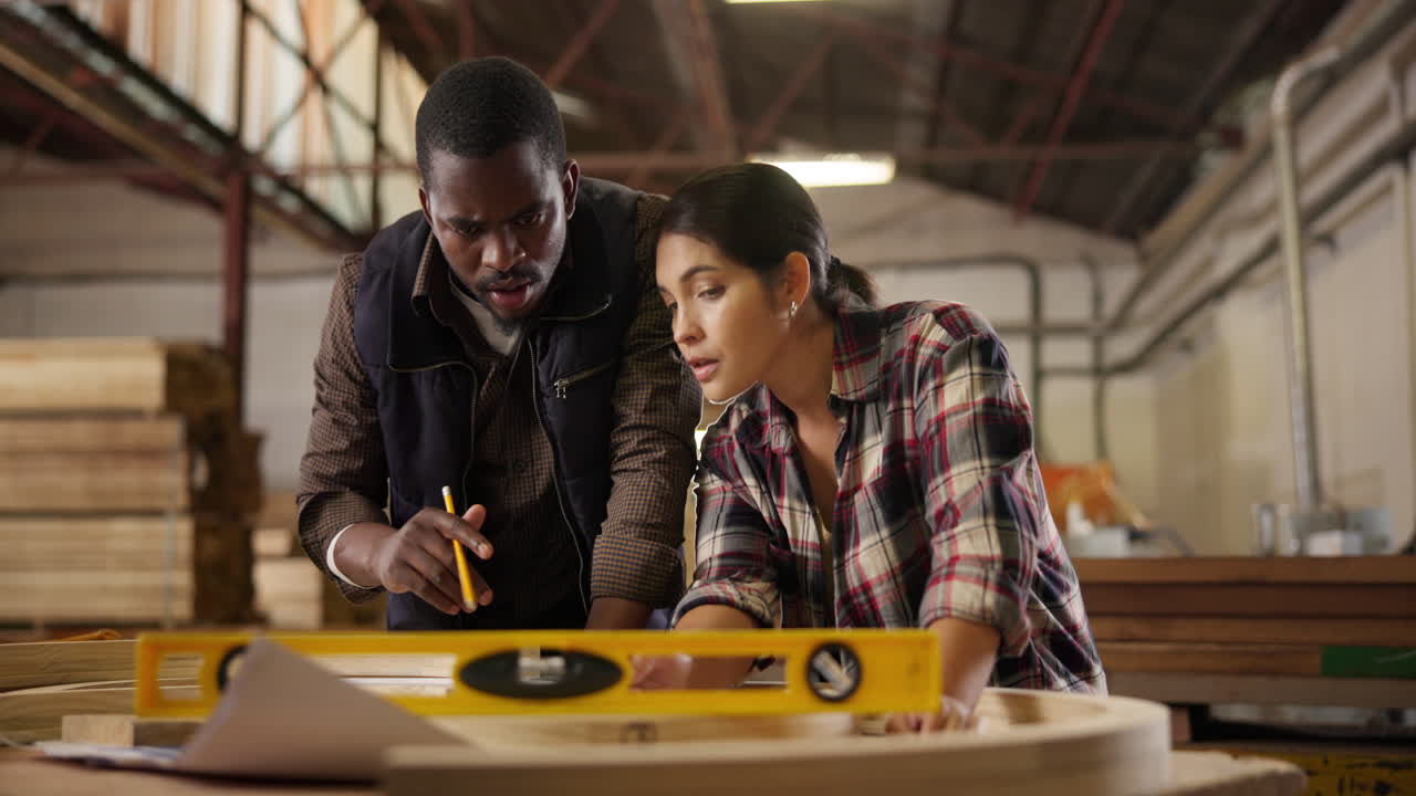 Carpenters collaborating on a design in a woodshop