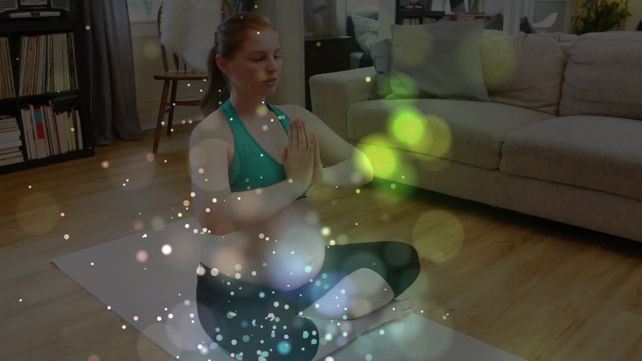 Animação de pontos de luz coloridos flutuando sobre mulher grávida caucasiana praticando ioga em casa