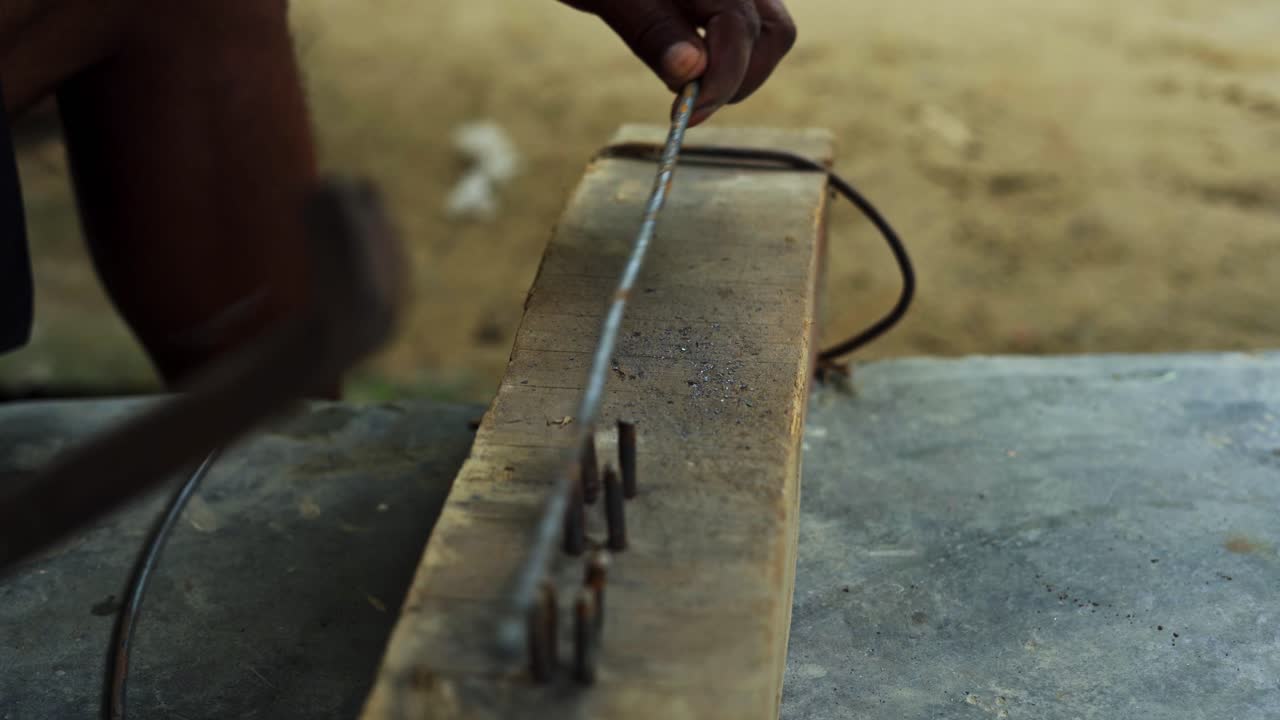 carpintero martillando una pieza de acero metal hierro en una aldea india rural remota cerca de las manos de artesanos