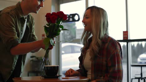 young man giving rose to woman in cafe 4k