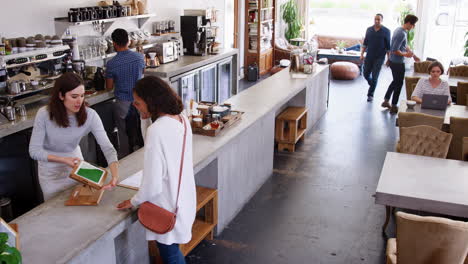 Staff-serving-customers-at-a-busy-coffee-shop,-elevated-view