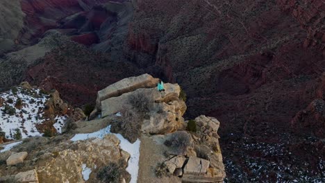 person on the peak of rock layers at grand canyon national park in arizona, united states