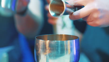 bartender pouring liqueur into jigger during making cocktail. barman equipment