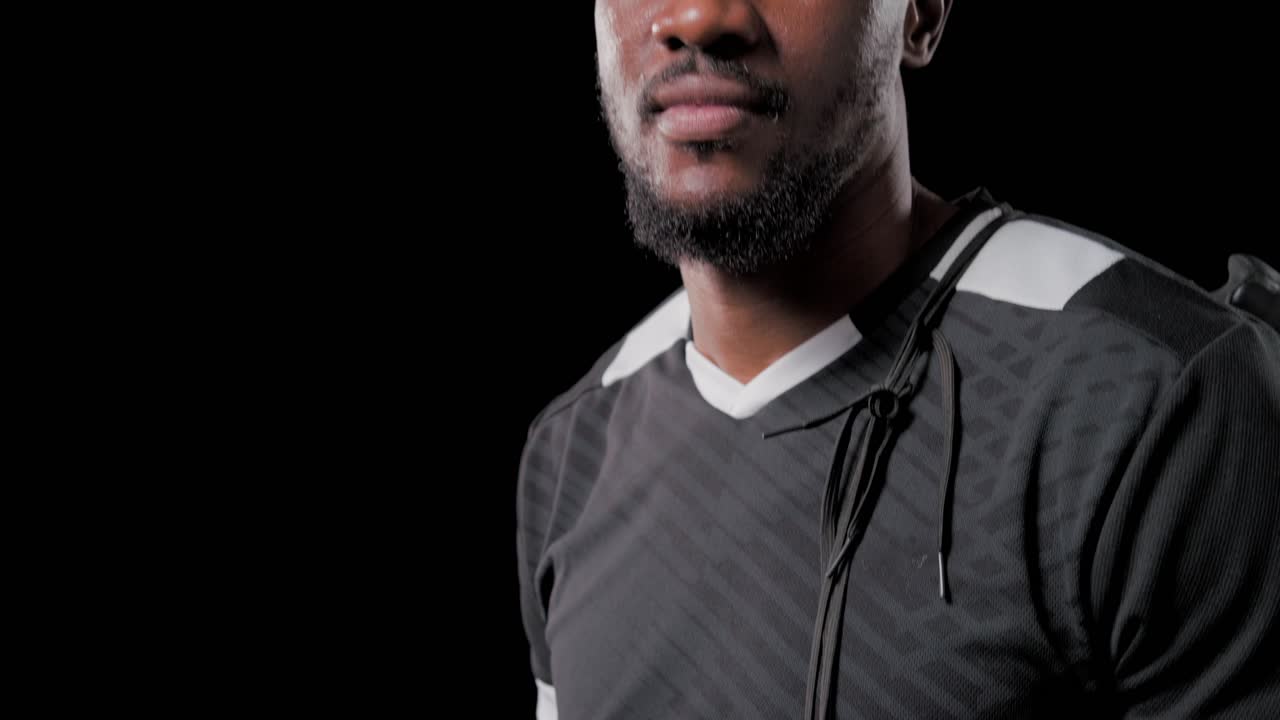 Uomo di mezza età in posa con una scarpa da calcio nera sul petto, mentre la fotocamera si allontana, mostrando la maglia, con spazio per il testo.