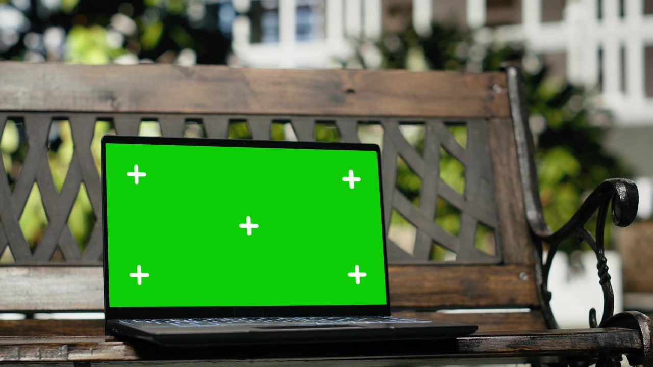 Primo piano di un laptop con schermo isolato su una panchina di legno vuota all'aperto in un parco cittadino.