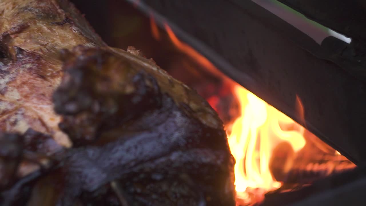 detalle de un jugoso cerdo asado giratorio asado al fuego dentro de una parrilla de metal