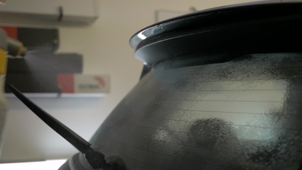 Window tinting spray over rear window of car cleaning