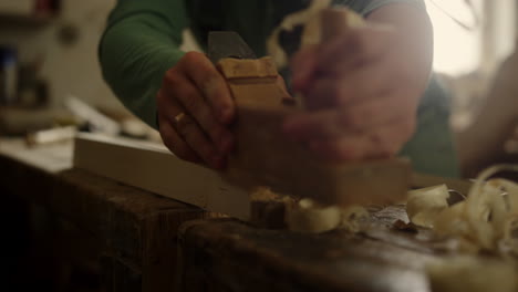 Unknown-carpenter-using-plane-in-workshop.-Craftmaster-hands-preparing-plank