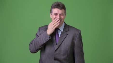 mature handsome businessman against green background