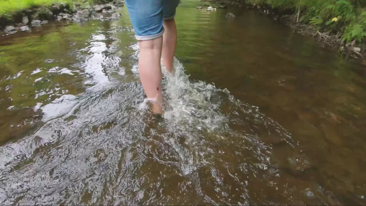 persona caminando en cámara lenta a través del agua de un arroyo en las ardenas, bélgica, europa, filmada en 2