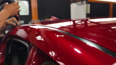 applying vinyl wrap to a red car roof