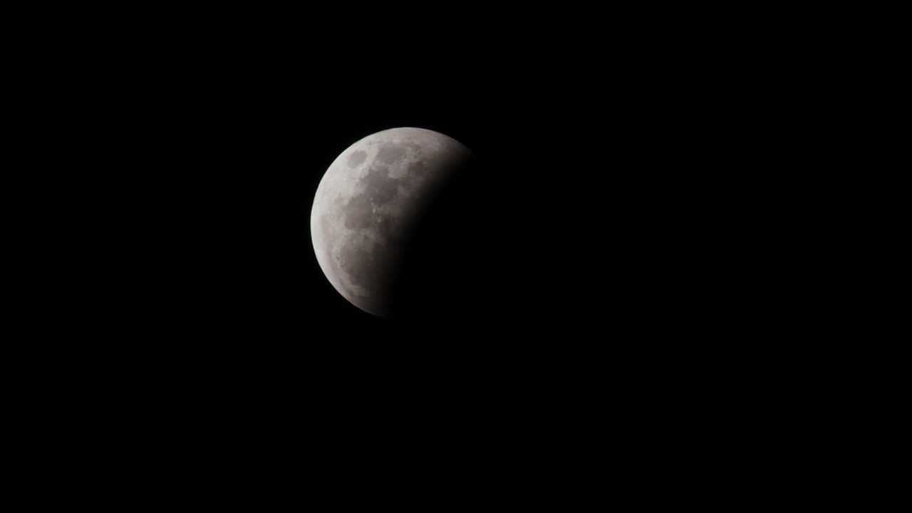A close up of the moon at first quarter phase, half illuminated with light and darkness in a pitch black sky