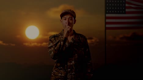 soldado en uniforme de camuflaje con el dedo en los labios al atardecer