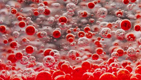 many small red bubbles floating in water, slowly sinking