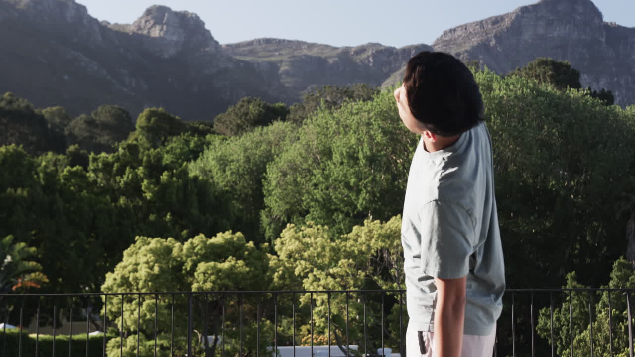 Asian man enjoying scenic mountain view on sunny day outdoors, on balcony, copy space