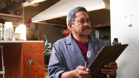 shoemaker reading clipboard in workshop