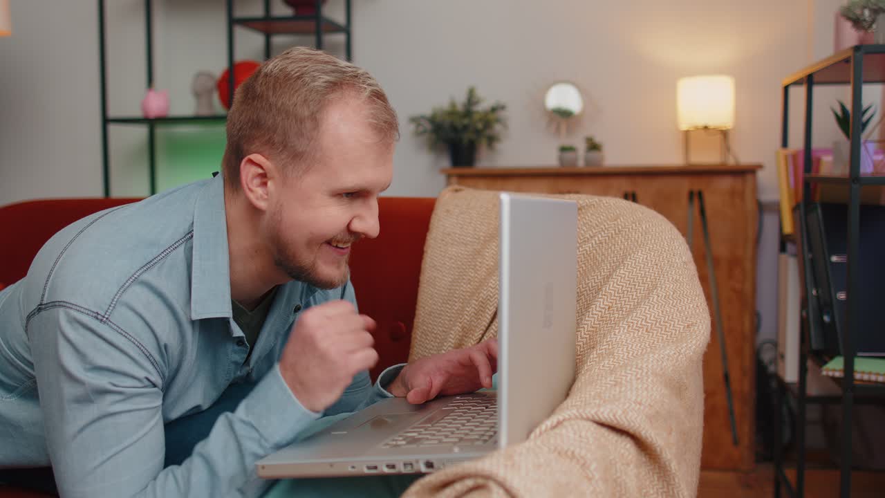 Young adult man at home office use laptop pc typing browsing say wow yes found out great big win