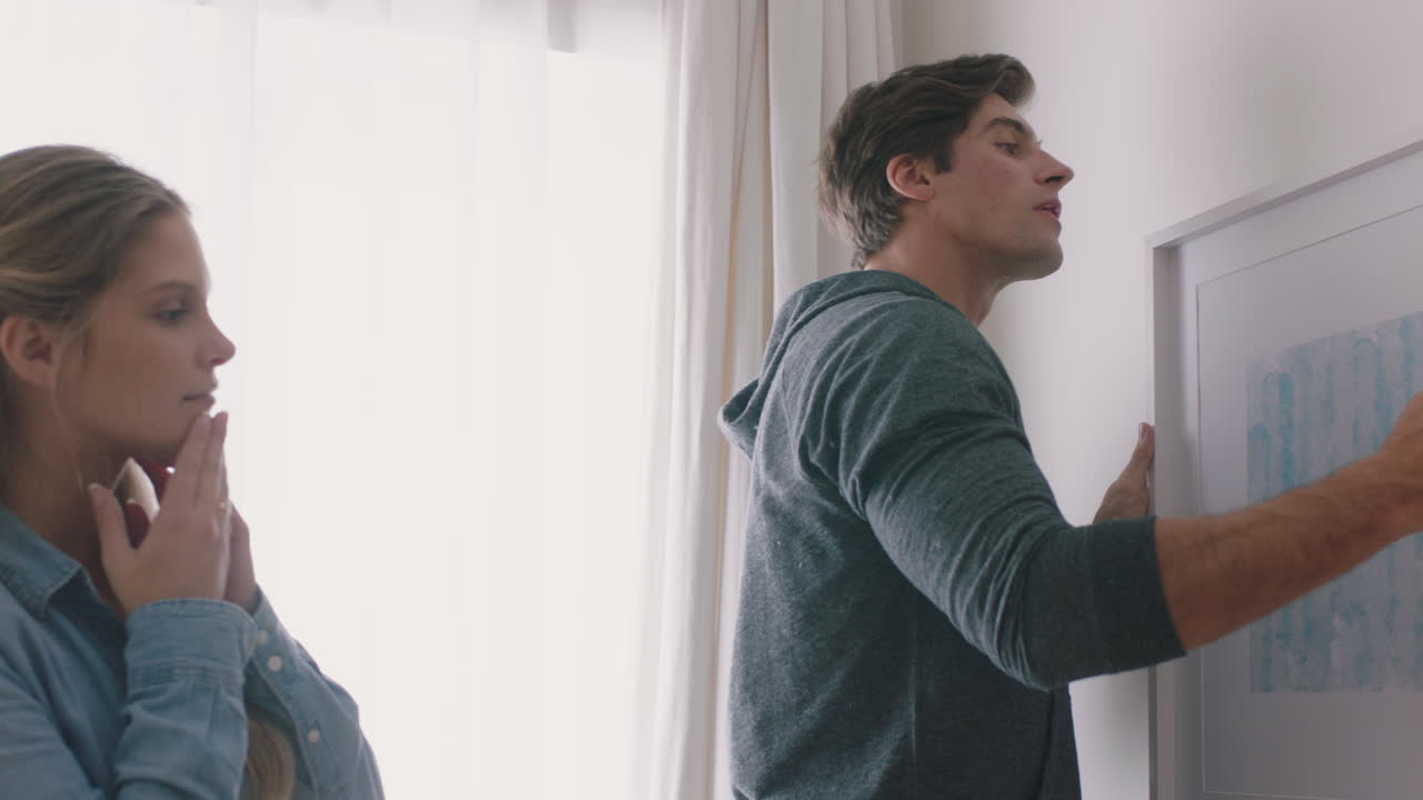 행복한 가족이 새로운 집으로 이사합니다. 주인들은 사진을 걸고 아이들과 함께 집을 꾸미고 있습니다. 젊은 부부는 아이들과 함께 부동산 투자를 즐기고 있습니다. 4k 영상