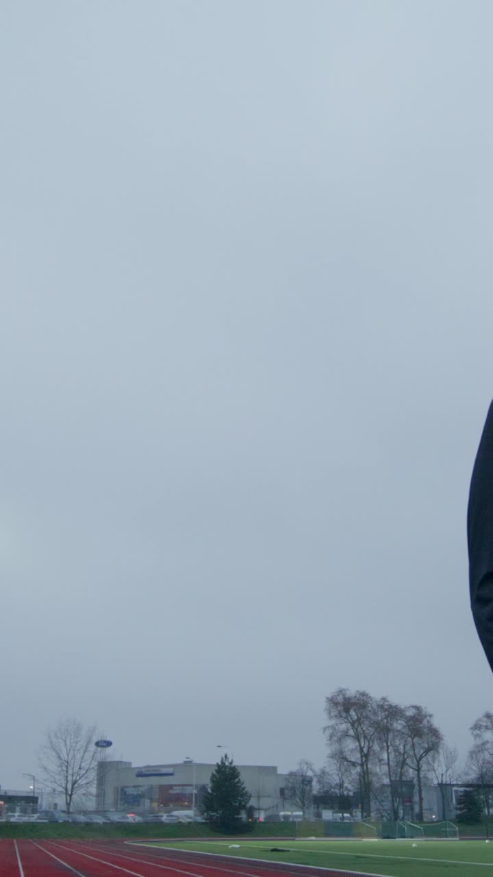 구름이 많은 날 경기장에서 트랙에 서 있는 사람