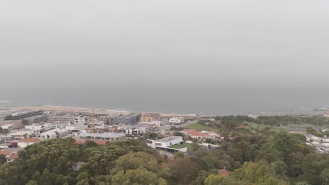 aerial - view of vila nova de gaia beach with buildings, trees, and foggy coastline in portugal