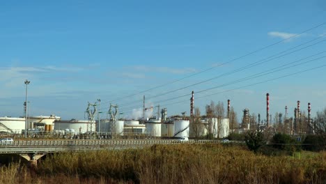 traffic on the road in front of a fuel refinery near the sea, real time shot, pollution concept