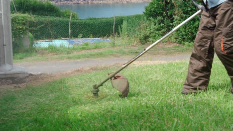 hombre mayor cortando el césped con un cortacésped