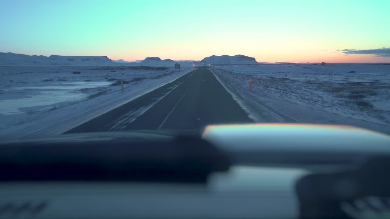 Driving on icy roads in Iceland in the winter towards the sunrise in February