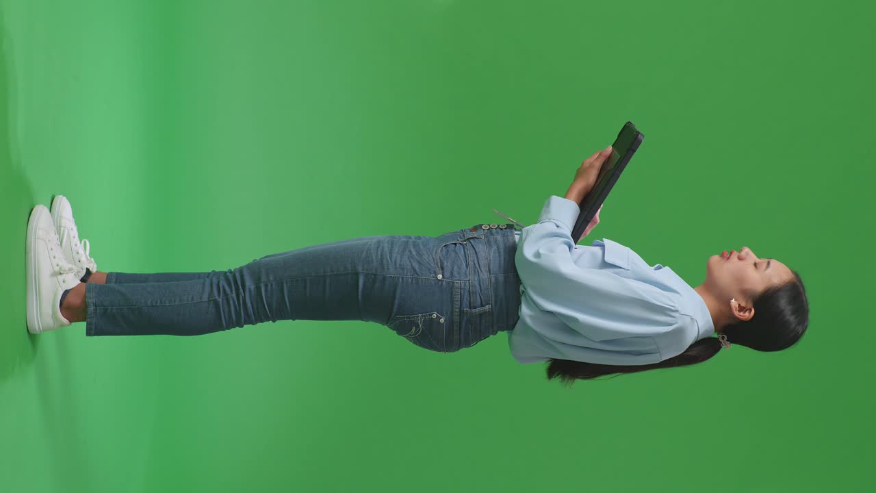 녹색 화면에 프로필 뷰에서 태블릿을 들고 있는 여성