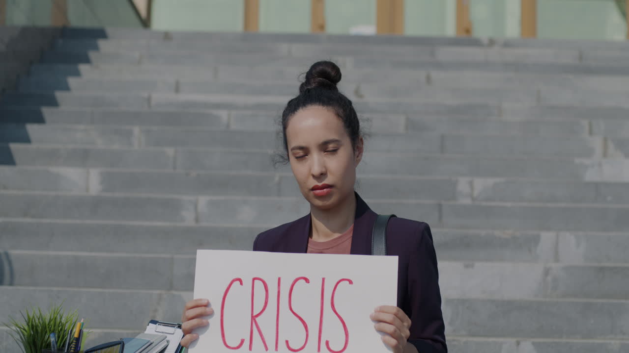 Woman holding a sign that says "Crisis" on stairs