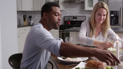 una pareja romántica de raza mixta haciendo un brindis en la comida en la cocina, filmado en r3d