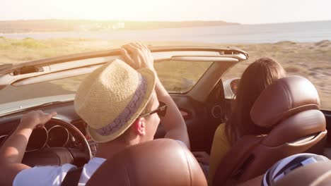 couple enjoying a scenic road trip in a convertible car by the sea