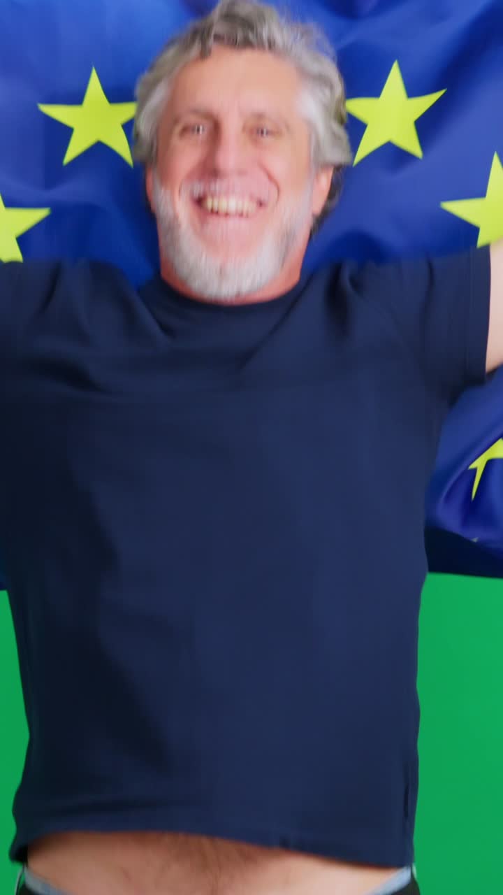 Uomo maturo felice che tiene e si avvolge nella bandiera dell'Unione Europea