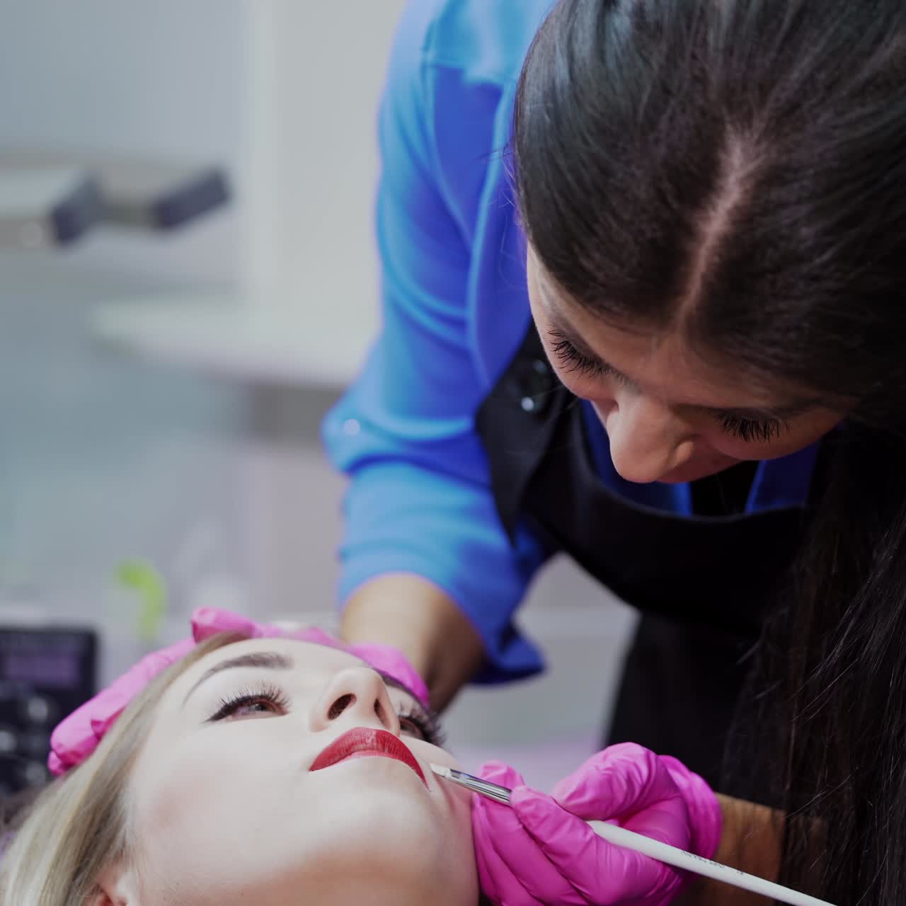 Lips tattooing in a beauty salon. Professional cosmetologist preparing woman's lips before the procedure of permanent makeup.