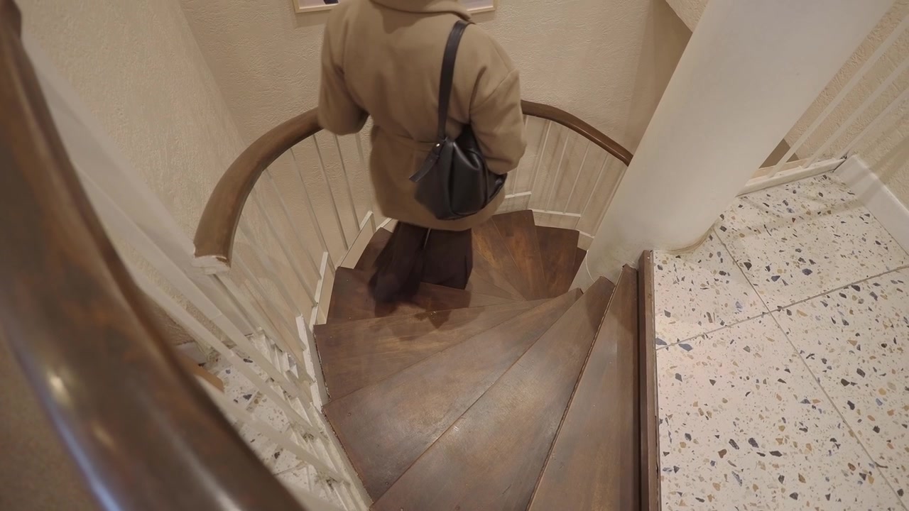 Donna che scende una scala a chiocciola con un cappotto elegante